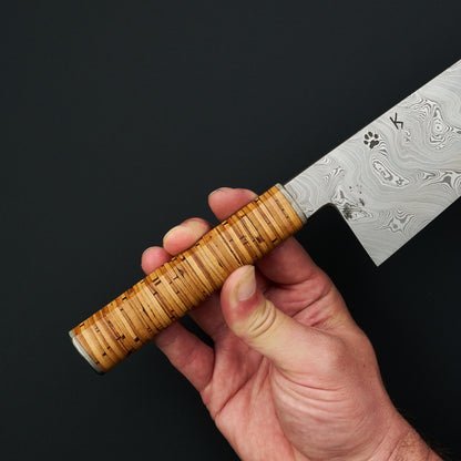 Stacked birch-bark takedown handle with stainless-steel bolsters, held in hand
